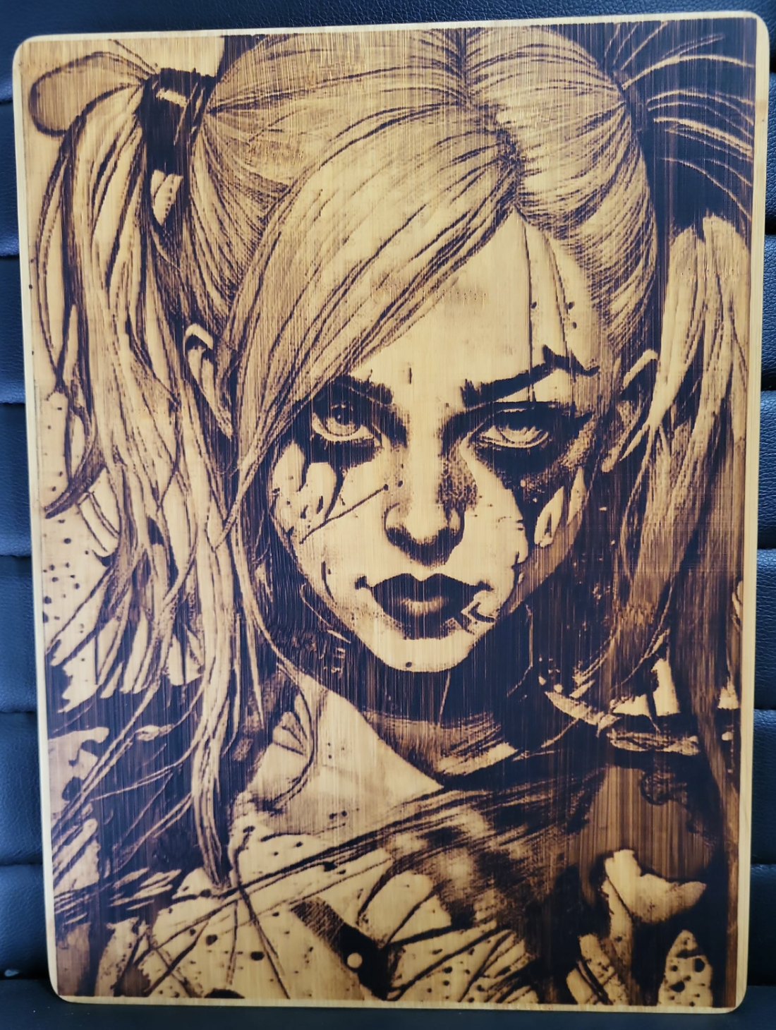 Wooden plaque with a stylized portrait of a character with blonde hair and dark makeup.